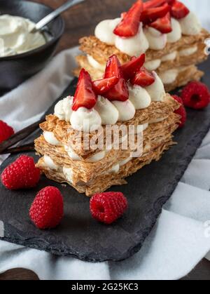 Fraises, framboises et crème mille feuille sur assiette en pierre noire Banque D'Images