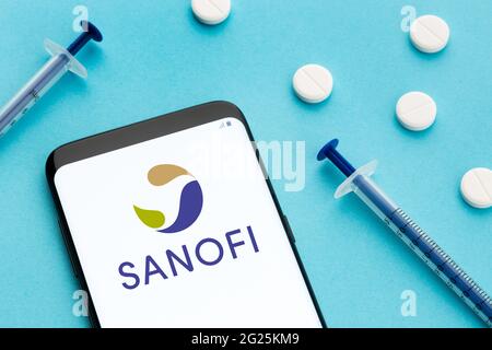 Galice, Espagne; 8 juin 2020 : smartphone affichant le logo Sanofi à l'écran et pilules et seringue sur fond bleu Banque D'Images