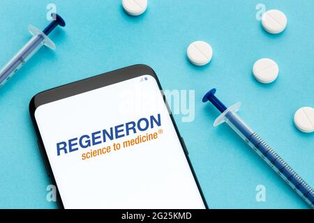 Galice, Espagne; 8 juin 2020 : smartphone montrant le logo Regeneron à l'écran et les pilules et la seringue sur fond bleu Banque D'Images