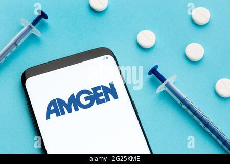 Galice, Espagne; 8 juin 2020 : téléphone intelligent avec logo Amgen à l'écran et pilules et seringue sur fond bleu Banque D'Images