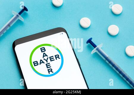 Galice, Espagne; 8 juin 2020 : smartphone montrant le logo Bayer à l'écran et les pilules et la seringue sur fond bleu Banque D'Images