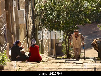 Scène de la rue turque dans le quartier de Fath à Istanbul, Turquie. Les femmes Turkisj sont assises sur des marches abruptes de la rue ; homme tirant le chariot. Banque D'Images