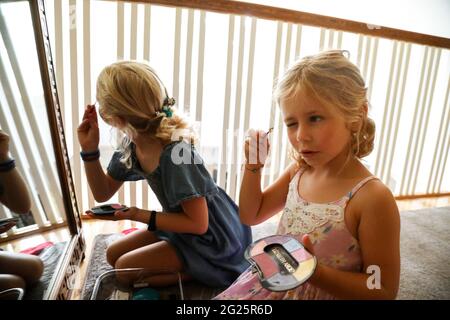 petites filles regardant dans le miroir de mettre sur le maquillage Banque D'Images