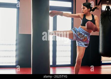 Une femme s'entraîne avec un sac de poinçonnage dans un gymnase Muay Thai Banque D'Images