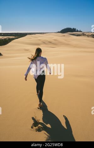 Une femme qui s'est mise à pied dans les dunes avec un maillot blanc et un collant Banque D'Images