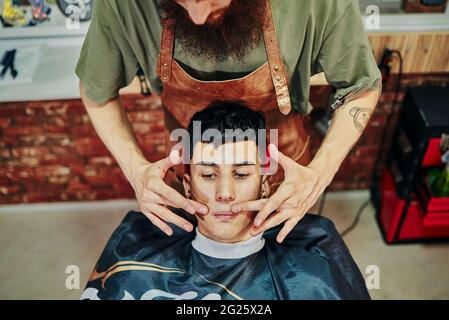 Un jeune homme dans la barbershop se fait masser la moustache. Banque D'Images