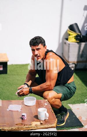 Un homme fort se repose sur la barbell dans la salle de sport extérieure Banque D'Images