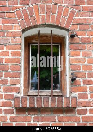 Vieille fenêtre avec barres de fer dans un mur de pierre de brique Banque D'Images