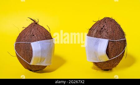 Masque de noix de coco. Sécurité dans les pays tropicaux. Coronavirus COVID-19. Distance sociale en vacances. Espace pour le texte. Une idée créative. Banque D'Images
