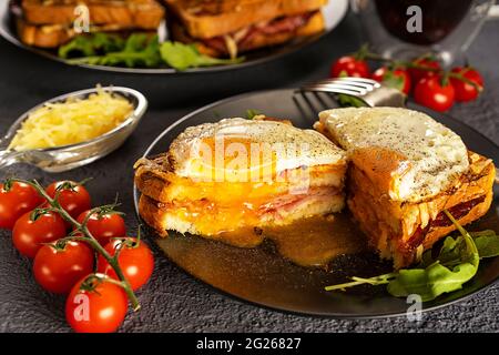 Sandwich chaud français pour le petit déjeuner. Croque madame sandwich. Sauce bechamel. Œuf frit. Plats dépolis, tomates cerises sur une branche. Banque D'Images