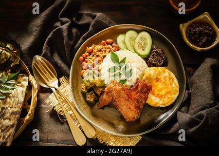 Nasi Lemak. Plat de riz malais de riz parfumé au poulet frit, pâte de Chili, arachides, anchois, œuf. Banque D'Images