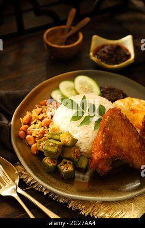 Nasi Lemak. Plat de riz malais de riz parfumé au poulet frit, pâte de Chili, arachides, anchois, œuf. Banque D'Images