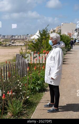 Une femme âgée marche sur la plage en Bretagne Banque D'Images