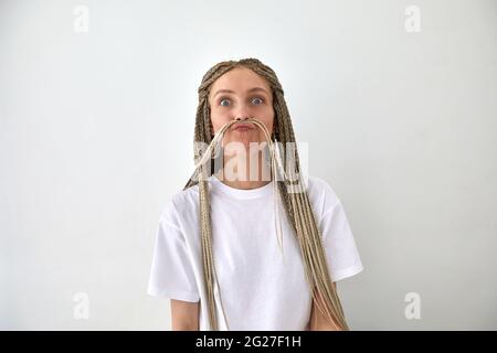 Femme avec de longs cheveux tressés donnant des lèvres jouer sur fond blanc et regardant l'appareil photo Banque D'Images