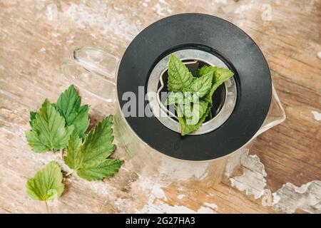 feuilles de menthe et raisins de corinthe pour le thé. Thé sain provenant de plantes de jardin. Transférez le mélange obtenu dans une théière, ajoutez le thé à la feuille noire et quelques menthe Banque D'Images