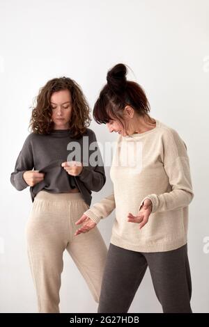 Les femmes d'âge moyen et les jeunes femmes portant des pantalons décontractés et des sweat-shirts en laine naturels debout sur fond blanc Banque D'Images