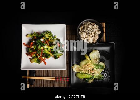 Cuisine végétarienne asiatique sur fond sombre vue de dessus. Emballez les légumes et le moule à riz pour faire sauter le choy sur une table noire Banque D'Images