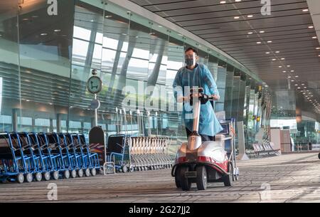 Singapour, le 8 juin 2021 - un employé de l'aéroport recueille des laissez-passer par un terminal de départ très calme à l'aéroport Changi de Singapour. Tout le personnel de l'aéroport porte des blouses de protection individuelle, des masques et des lunettes dans les terminaux d'arrivée et de départ. Avant la pandémie de Covd-19, en 2019, l'aéroport de Changi était le septième aéroport le plus occupé par le trafic international de passagers dans le monde et le troisième en Asie. Crédit : Rob Taggart/Alay Live News Banque D'Images