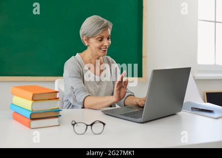 Formation en ligne. Un professeur senior s'adresse aux élèves tout en communiquant sur un ordinateur portable en classe. Un tuteur mûr donne une leçon Banque D'Images