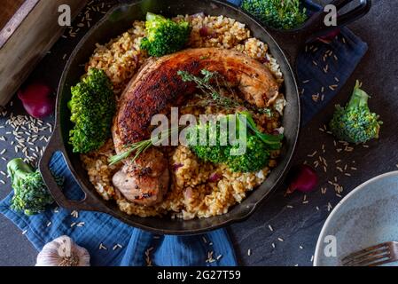 Repas santé bon régime repas de remise en forme à faible teneur en gras avec filet de porc rôti, riz brun et brocoli servi dans une poêle rustique en fonte d'en haut. Banque D'Images