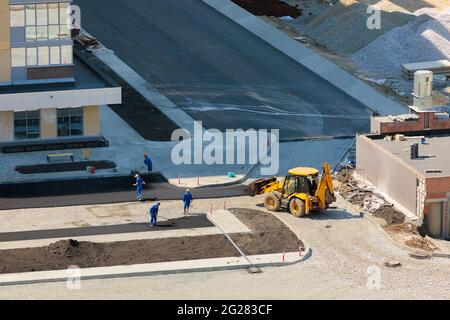 Les travailleurs de l'équipement spécial ponent de l'asphalte près d'une maison en construction. Chelyabinsk, Russie, 17 mai 2021 Banque D'Images