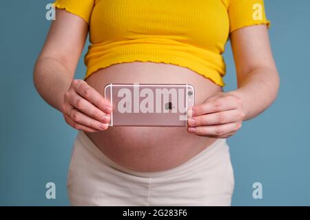 Tournage de vidéos et de photos sur un iPhone d'Apple dans les mains d'une femme enceinte - Moscou, Russie, 23 avril 2021 Banque D'Images