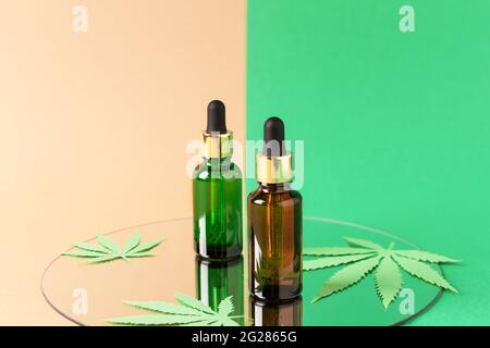 Extrait d'huile de cannabis en flacons de gouttelettes sur fond vert et marron double couleur sur miroir. Huile de CBD de marijuana médicale. Médecine alternative, à base de plantes Banque D'Images