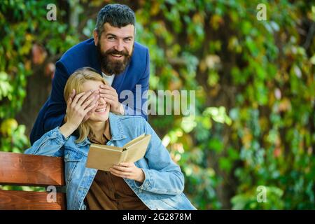 Une jeune fille excitée qui essaie de deviner qui se tient derrière elle. Un petit ami qui lui couvre les yeux par les mains et souriant. Une ambiance de printemps ludique. Surprise. Couple heureux Banque D'Images