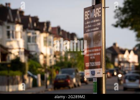 Maisons suburbaines sous le soleil du soir et un panneau d'avertissement du Conseil de Lambeth par le Conseil de Lambeth, d'amendes et de poursuites pour terniement et pourboires, le 7 juin 2021, dans le sud de Londres, en Angleterre. Banque D'Images