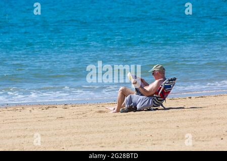 Bournemouth, Dorset, Royaume-Uni. 9 juin 2021. Météo au Royaume-Uni : matin chaud et ensoleillé sur les plages de Bournemouth, tandis que les amateurs de soleil se dirigent vers le bord de mer pour profiter du soleil. Homme lisant le quotidien. Crédit : Carolyn Jenkins/Alay Live News Banque D'Images