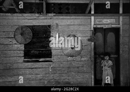 Sungai Uluk Palin, Kapuas Hulu, Kalimantan occidental, Indonésie. Mars 2007. Portrait d'un enfant à la porte d'entrée de la résidence d'une famille à la maison de la communauté traditionnelle Dayak Tamambaloh.--photographié sur film noir et blanc, numérisé, numérisé. Banque D'Images