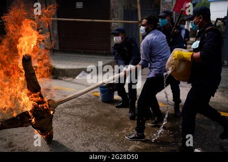 Katmandou, Népal. 9 juin 2021. Le personnel de police tente d'éveiller une effigie du Premier ministre du Népal, KP Sharma Oli, incendiée par l'alliance de l'opposition lors d'une manifestation contre la dissolution du Parlement, le remaniement ministériel et des élections anticipées dans le cadre du confinement de la pandémie du coronavirus à Katmandou, au Népal, le mercredi 9 juin 2021. Crédit: Skanda Gautam/ZUMA Wire/Alay Live News Banque D'Images