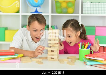 Frère et sœur jouant avec des blocs de bois dans la salle de jeux Banque D'Images