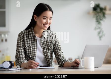 Femme asiatique souriante étudiant utilisant un ordinateur portable pour étudier à la maison Banque D'Images