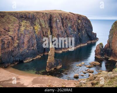 Falaises de granit rouge et pile de mer sur Muckle Roe, Shetland, Royaume-Uni - ces roches sont de l'intrusion de Muckle Roe - granite, granophyrique - roches ignées Banque D'Images
