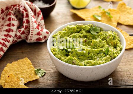 Gros guacamole maison dans un bol avec des chips de tortilla Banque D'Images