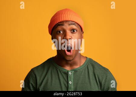 Offre choquante. Gros plan Portrait d'un petit homme de taille basse noir émerveillé dans un chapeau orange Banque D'Images