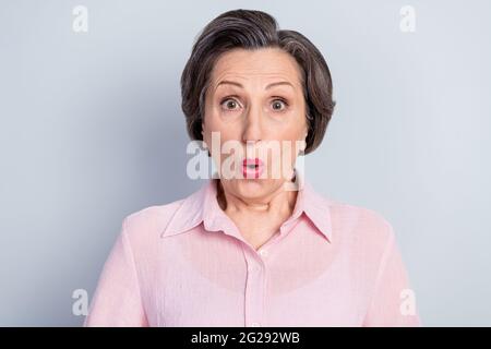 Photo de choqué drôles matures dame porter des vêtements roses grands yeux lèvres pouted isolé couleur de fond gris Banque D'Images