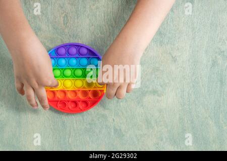 garçon appuyant sur des bulles de silicone souples et colorées en arc-en-ciel. Enfant jouant avec le jouet sensoriel pop IT. Soulagement du stress et de l'anxiété. Jeu de violon tendance. Banque D'Images