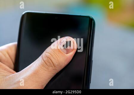 Gros plan d'un homme utilisant un smartphone mobile. La flèche sur l'ongle pointe vers l'écran du smartphone. Un homme avec une manucure touche sur l'écran du smartphone Banque D'Images