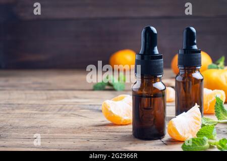 Huile de mandarine aromatique dans une bulle sombre, huile cosmétique de mandarine sur fond de bois, espace de copie Banque D'Images