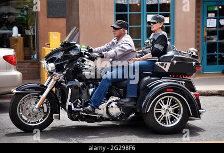 Un couple senior fait un tour de Harley-Davidson Trike Tri-Glide à travers la place historique de Santa Fe, Nouveau-Mexique. Banque D'Images