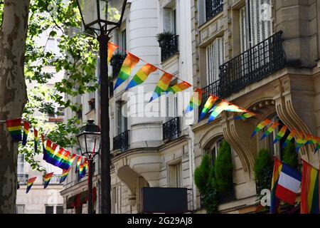 Décoration de bannières en forme de triangle dans les couleurs des drapeaux LGBTQ accrochés entre lanternes d'époque et maison ornée avec balcons. Fierté gay Banque D'Images