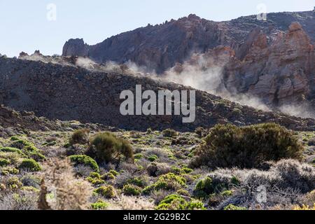 Nuage de poussière rétroéclairé derrière un véhicule en mouvement sur une piste dans le parc national de Las Canadas del Teide, Tenerife, Îles Canaries, Espagne Banque D'Images