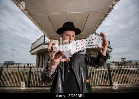 Le magicien Guy Parker tente de faire fleurir un Card Spring lors d'une journée venteuse le long du bord de mer de Brighton, dans le Sussex, en Angleterre, au Royaume-Uni Banque D'Images