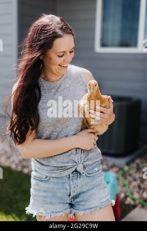 Une femme tient du poulet dans son jardin un jour ensoleillé Banque D'Images