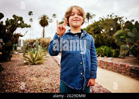 Portrait d'un garçon souriant montrant un panneau de corne en se tenant debout dans le parc Banque D'Images