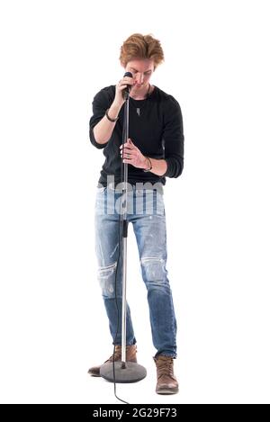 Jeune homme élégant bascule préparer et régler le microphone avant le concert. Longueur totale du corps isolée sur fond blanc. Banque D'Images