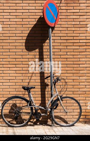 Vélo d'époque appuyé contre un panneau de signalisation sur un mur de briques orange Banque D'Images