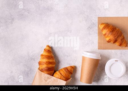 Café à emporter dans une tasse de papier avec croissants, vue de dessus. Banque D'Images